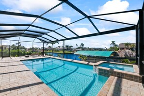 Ein überdachter Pool mit Blick auf Palmen und ein Gebäude in der Ferne.