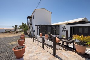 Ein Terrassenbereich mit Terrakotta-Pflanzgefäßen, einem Holzzaun und einem Gebäude mit der Aufschrift 'Villa Spa La Indio'.