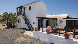 En vit byggnad med en balkong, en trappa och en skylt med texten ”Villa Spa los Tingas”.