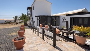 En uteplats med terrakottafärgade blomkrukor, ett staket av metall och en byggnad med en skylt som visar texten ”Villa Spa La Indio”.