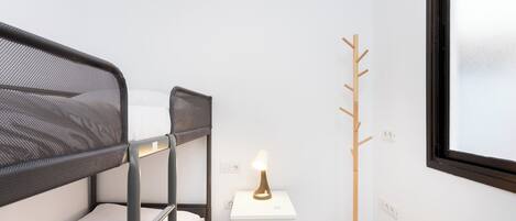 Dormitorio con literas, mesita de noche y perchero.