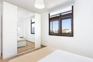 Ein Schlafzimmer mit einem Bett, einem Fenster, einem Spiegel und einem Kleiderschrank.