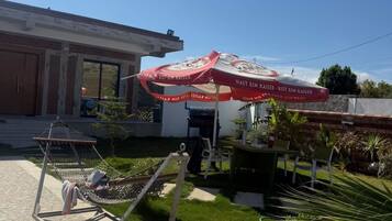 Un patio con una hamaca, una mesa con sillas y una parrilla.