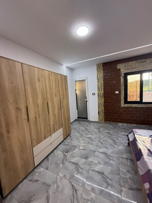 Een kamer met een inbouwkast, een deur, een bakstenen muur en een raam.