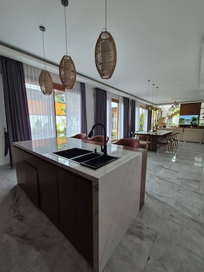 Amplio espacio de sala con una isla grande, muebles de cocina oscuros y una cocina moderna.