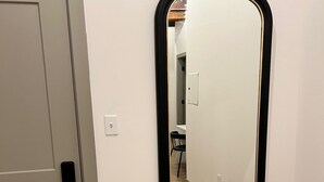 Habitació amb una porta, un mirall fixat a la paret i un interruptor.