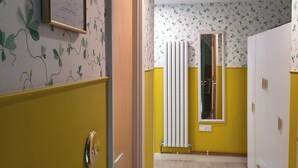 Een gang met een radiator, een deur en een ingelijst certificaat aan de muur.