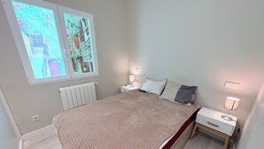 Et soveværelse med seng, to sengeborde, et vindue med udsigt og en radiator.