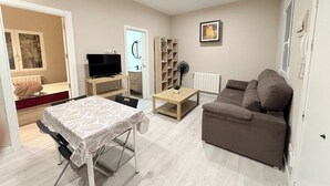 En stue med sofa, fjernsyn, bord og ventilator.