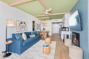 Ein modernes Wohnzimmer mit blauem Sofa, einem Esstisch und einem Kamin.