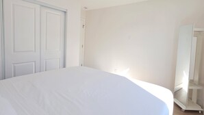 Un dormitorio con una cama grande, un armario y un espejo.