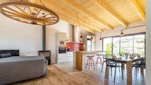 Une cuisine moderne dotée d’un îlot central, de tabourets de bar rouges et d’une table à manger avec des chaises.