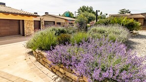 Un quartier résidentiel doté d’un jardin clos par un mur en pierre, d’un garage et de maisons aux toits en tuiles.