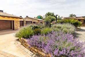 Ein Wohngebiet mit einer Steinmauer, einem Garten, einer Garage und Häusern mit Ziegeldächern.