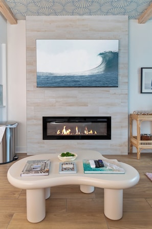Ein modernes Wohnzimmer mit Kamin, einem Wand-Fernseher und einem einzigartigen Tischdesign.