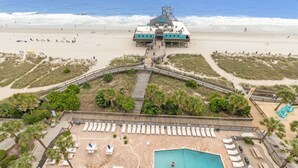 Un resort frente a la playa con un muelle, una piscina y sillas de playa.
