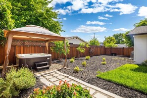 Ein Garten mit Whirlpool, überdachter Terrasse und gepflegtem Garten.