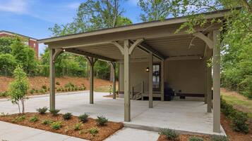 A covered outdoor area with a concrete floor, wooden pillars, and a small staircase leading to a door.