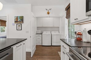 A laundry room with two washing machines, a drying rack, and a wall-mounted heater.
