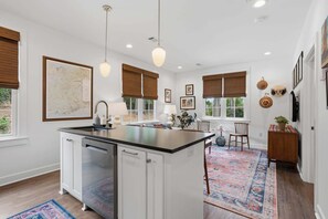 A modern kitchen with a central island, white cabinetry, and a dining area with a rug.
