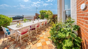 Eine Terrasse mit Tisch und Stühlen, eine Ziegelwand und ein Fenster mit der Nummer 20.