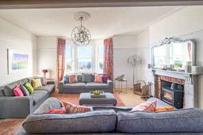 Ein Wohnzimmer mit Kamin, zwei Sofas, einem Couchtisch und einer Chandelüster.