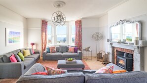 Una sala de estar con chimenea, dos sofás, una mesita de centro y un candelabro.