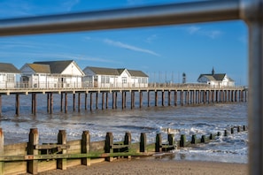 A pier with buildings, wooden posts, and a sandy beach. - Northcliffe (8), Southwold, Suffolk (Southwold)