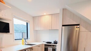Een moderne keuken met een ingebouwde oven, een roestvrijstalen koelkast en een raam met uitzicht op de omgeving.
