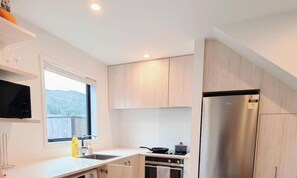 Eine moderne Küche mit Einbauofen, einem Edelstahl-Kühlschrank und einem Fenster mit Blick ins Freie.