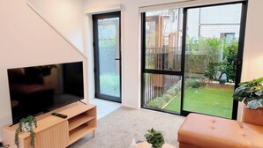 Een moderne woonkamer met een flatscreen televisie, een houten tv-meubel en een bank.