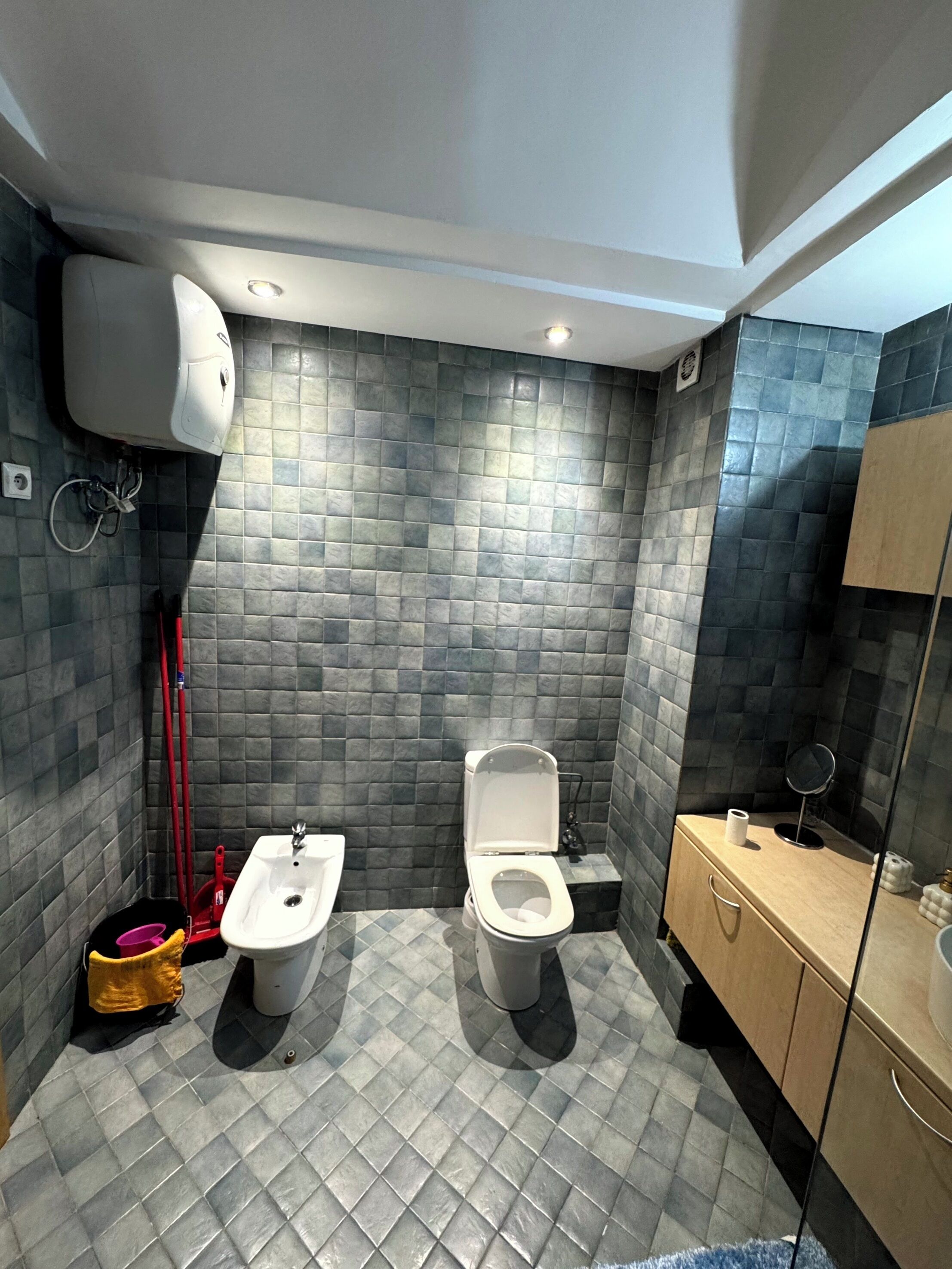 Ein Badezimmer mit zwei Toiletten, einem Waschbecken und einem Spiegel.