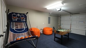 Ein Zimmer mit Basketballkorb, Kicker und orangenen Sitzsäcken.