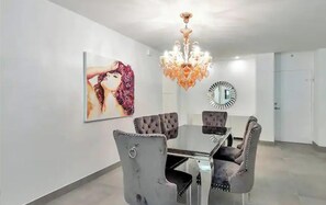 Ein Esszimmer mit einer Chandelüster, einem großen Spiegel und einem Gemälde an der Wand.
