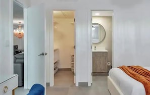 Ein Hotelzimmer mit Bett, Schreibtisch, Stuhl, Kleiderschrank und einem Badezimmer mit Waschbecken und Spiegel.
