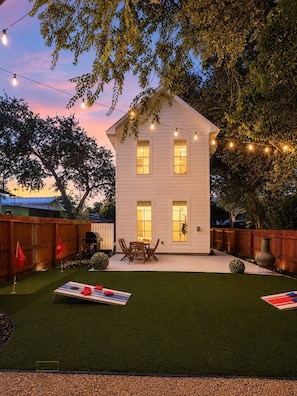 A two-story house with a patio area, a string of lights, and a small table with chairs. - Urban Casa at Olmos Park (San Antonio)