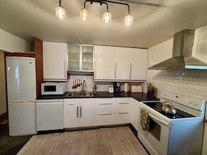 A kitchen with white cabinets, a microwave, a sink, a stove, and hanging lights. - Wonderful 2 bedroom/2 bath fully furnished suite steps from the Ocean (Victoria)
