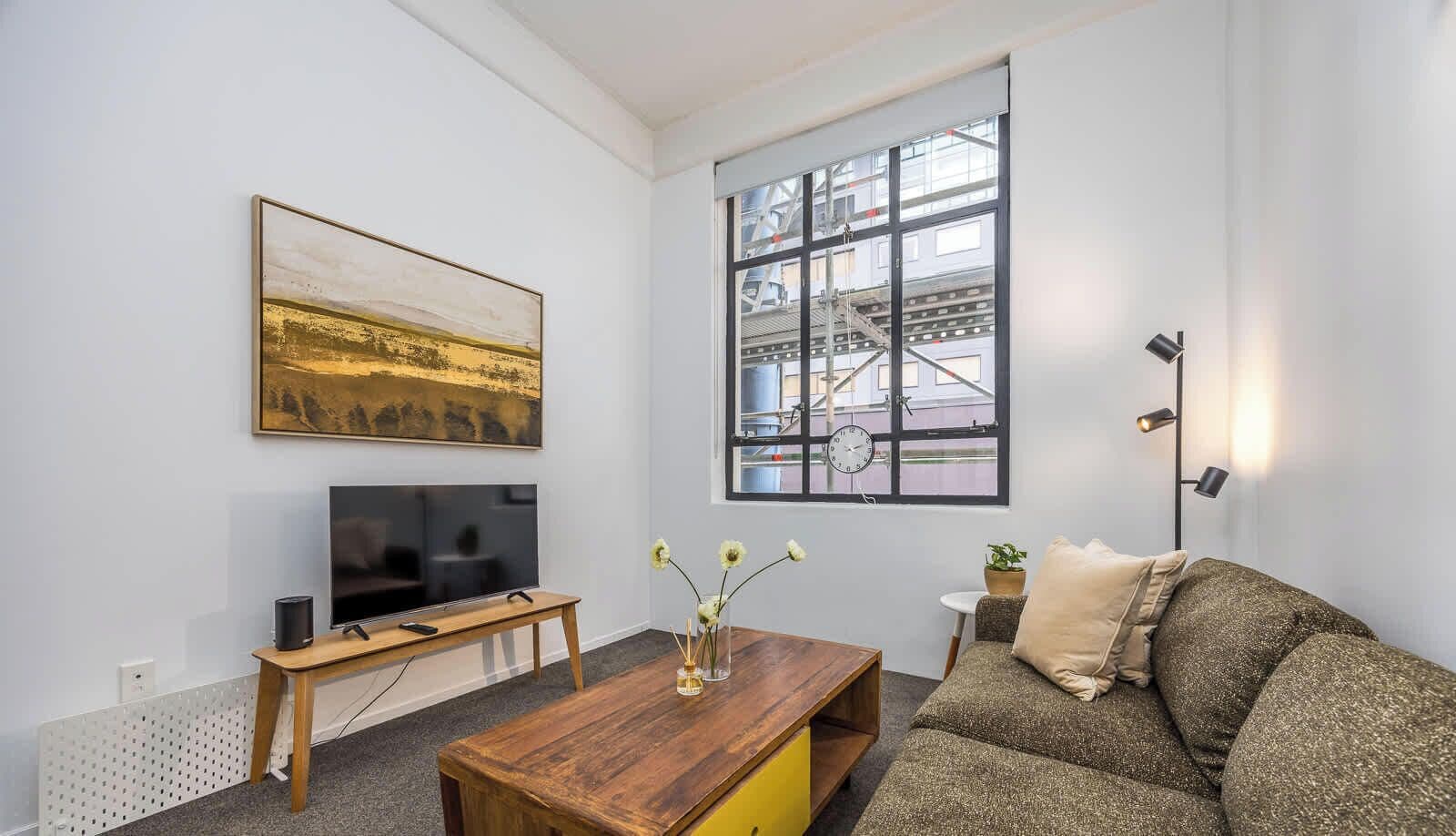 A living room with a TV, sofa, coffee table, and artwork on the wall.
