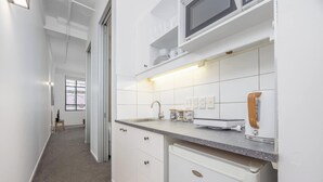 Una cocina moderna con armarios blancos, un lavamanos de acero inoxidable y un microondas.