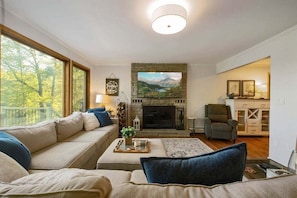 A living room with a fireplace, a sofa, a coffee table, and a television. - Spacious 7BR retreat with hot tub, fire pit, dock, and year-round views (Swanton)