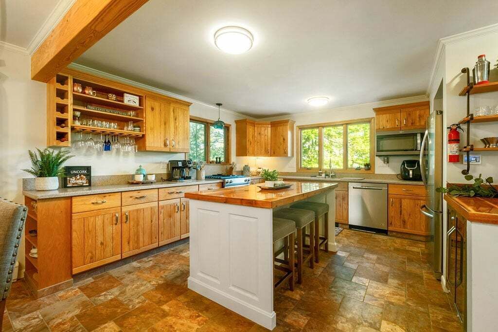 A spacious kitchen with wooden cabinets, a central island, and a large window providing natural light.