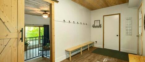 A room with wooden flooring, a bench, a door, and a wall-mounted coat rack.