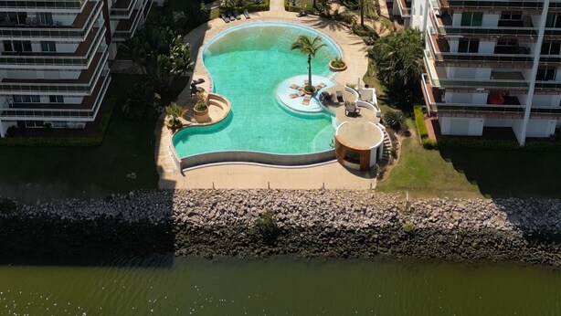 A high-rise building with a rooftop pool surrounded by palm trees and a marina in the background. - Pacifika Mazatlan Studio (Mazatlán)