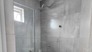 A modern bathroom with a glass-enclosed shower, a toilet, and a sink. - Pacifika Mazatlan Studio (Mazatlán)