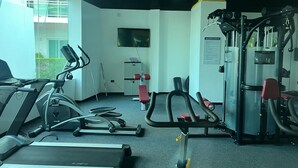 Une salle de sport équipée de machines de cardio, de matériel de musculation et d’un téléviseur fixé au mur.