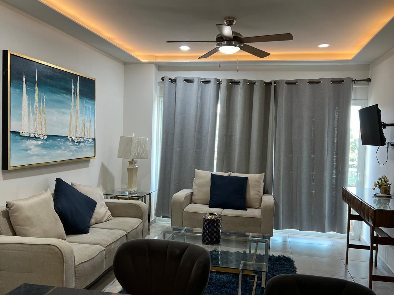 A living room with a sofa, armchair, coffee table, and a painting on the wall.