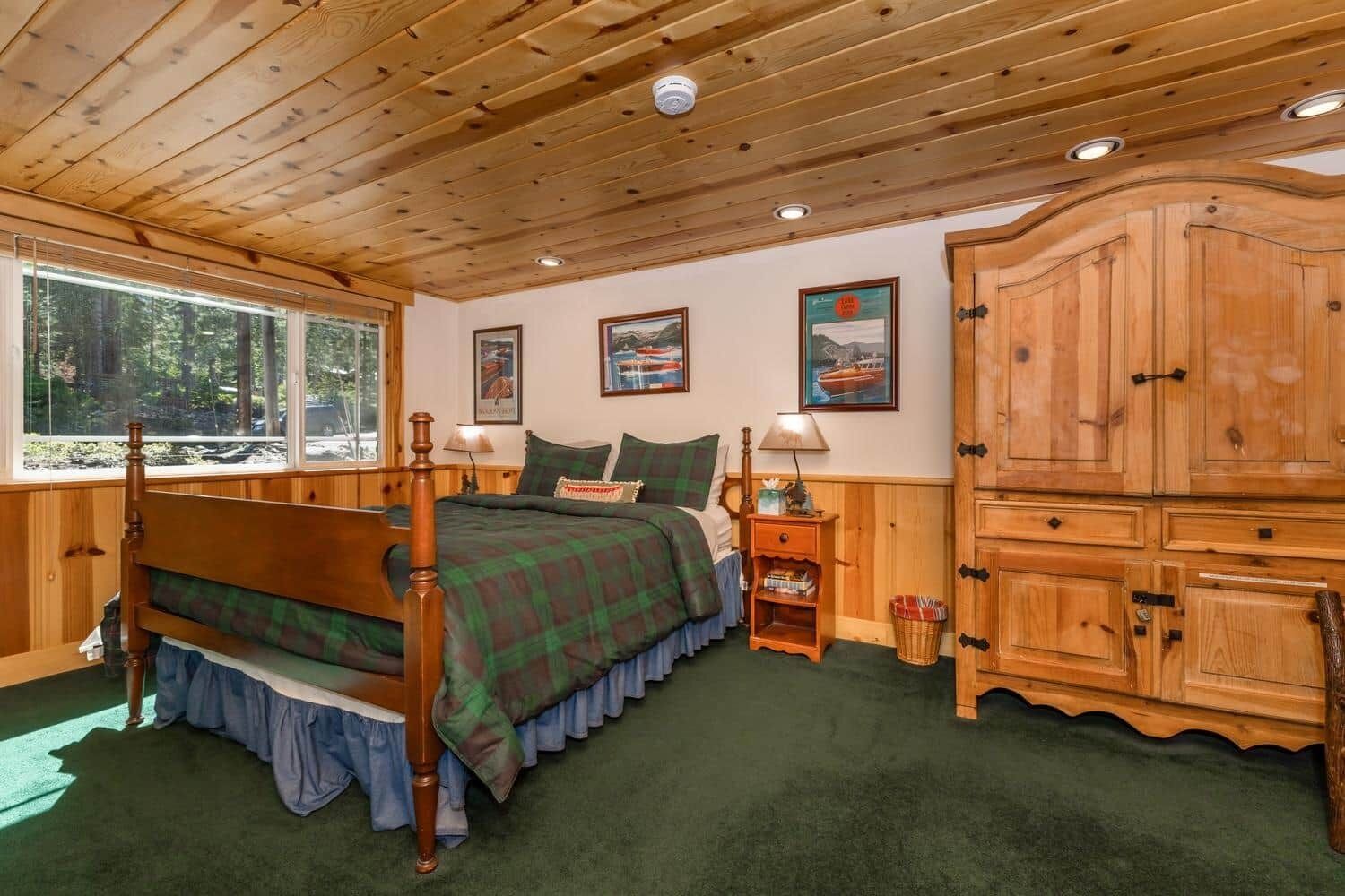 A wooden cabin bedroom with a bed, a nightstand, a cabinet, and a window.
