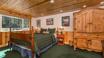 A wooden cabin bedroom with a bed, a nightstand, a cabinet, and a window.