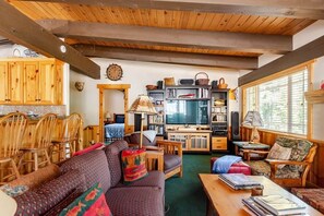 Un salon confortable avec un canapé, des fauteuils, une table basse, un téléviseur et une bibliothèque.