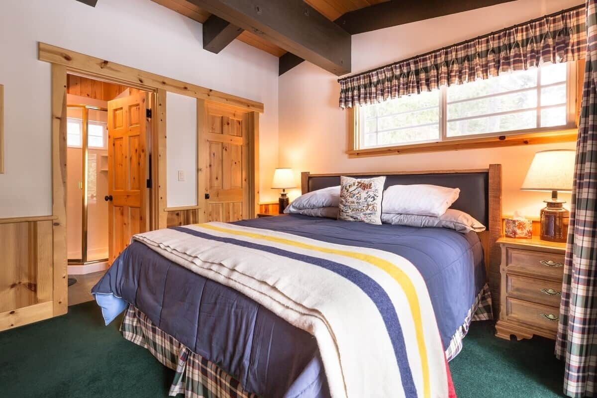 Une chambre à coucher avec un grand lit, des portes en bois, une fenêtre avec des rideaux et une table de chevet avec une lampe.